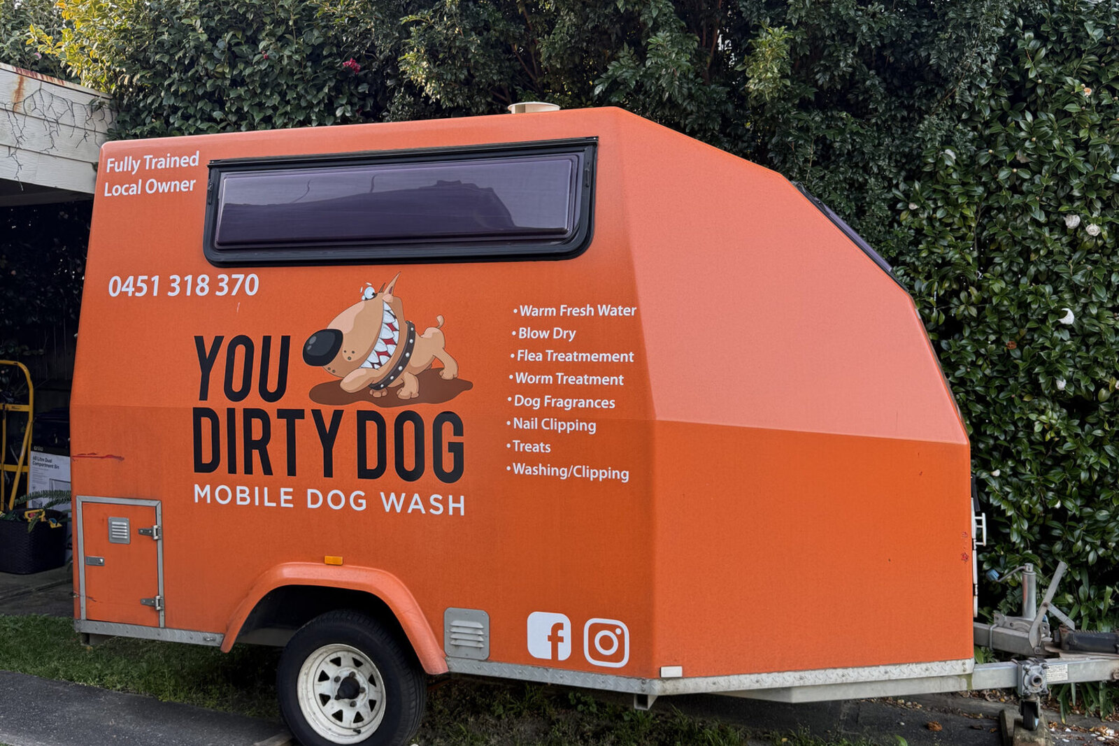 The orange You Dirty Dog trailer, service list painted along the side